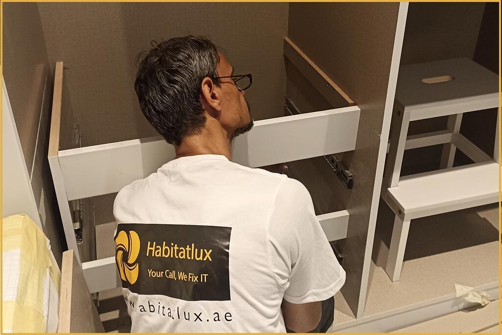 a male habitatlux worker working a carpentry work while sitting close to a wardrobe