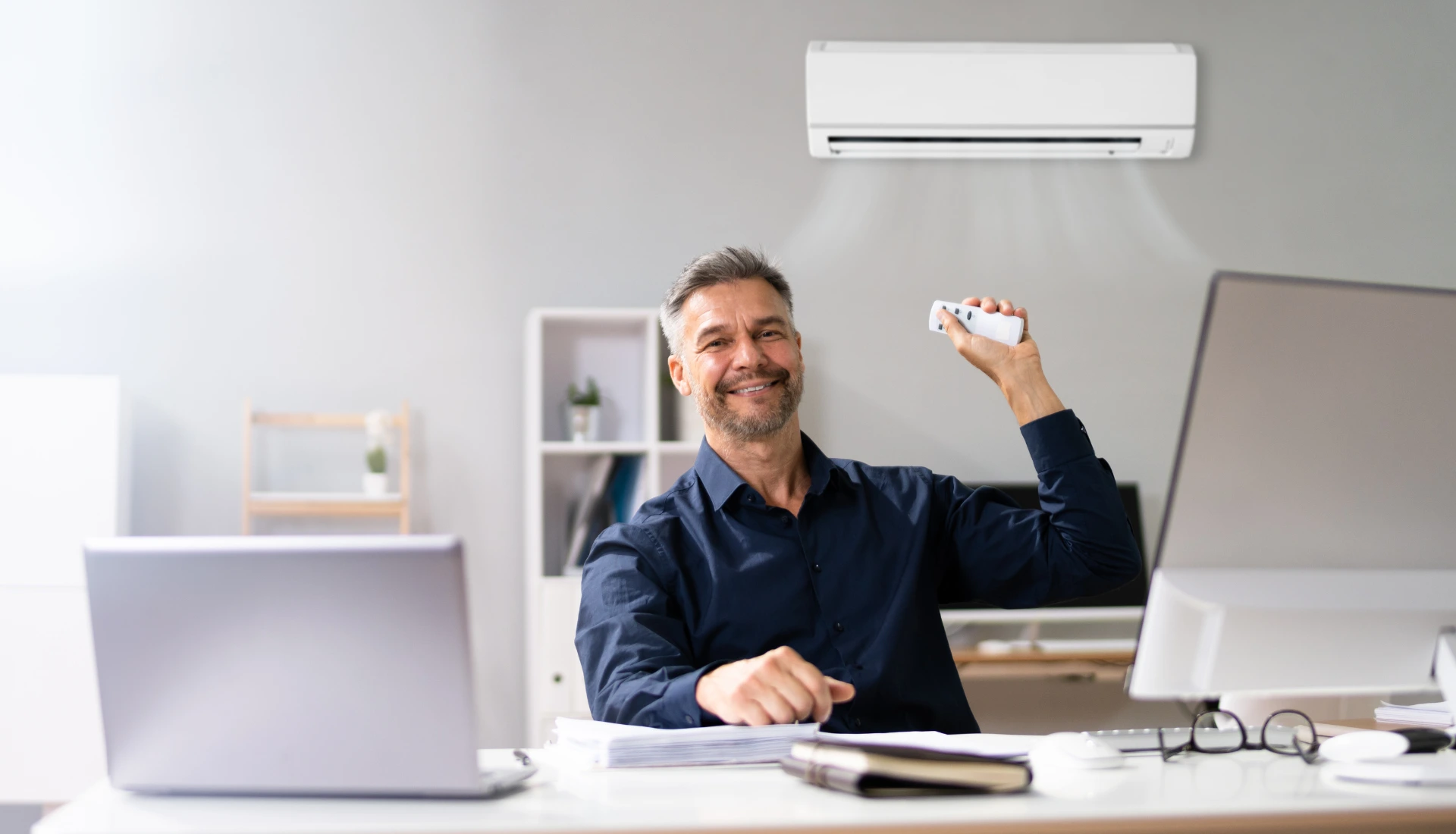 a man in a room having ac remote in hand and smiling